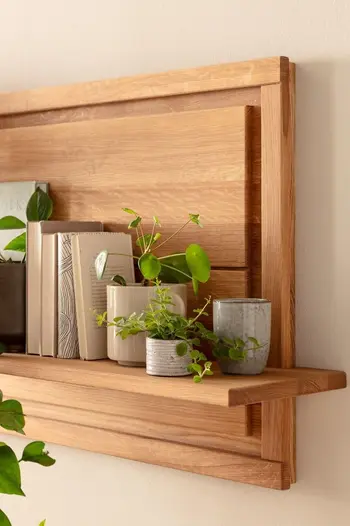 Rechter Teil eines hängenden Wandregals aus massiver Eiche, dekoriert mit Büchern und kleinen Pflanzen in grauen und beigen Töpfen.
