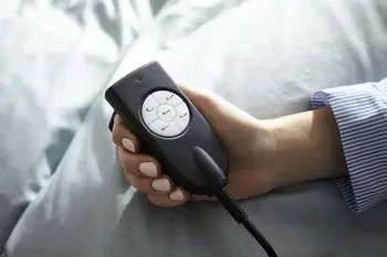 Eine Hand hält eine Fernbedienung eines Boxspringbettes, zur Verstellung der Liegehöhe.