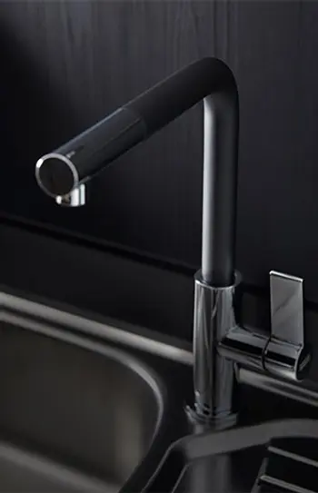 Einhebelarmatur vor dunkler Küchenrückwand.