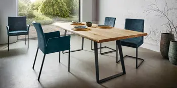 Hoelzerner Tisch mit petrolfarbenen Stuehlen.