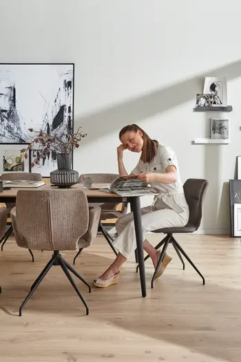 Grauer moderner Armlehnstuhl, der an einem Wildeiche Esstisch steht, an dem eine Frau sitzt.