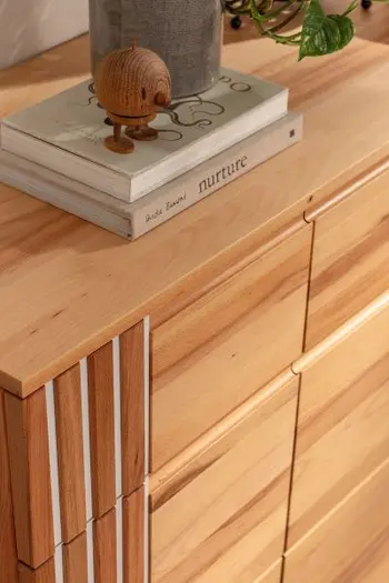 Kommode aus hellem Holz in Buche mit Lamellenakzente auf der linken Seite.