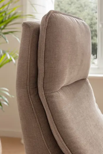 Seitliche Aufnahme der bequem gepolsterten Kopflehne eines beigen Relaxsessels.