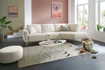 Beiges Ecksofa mit passendem runden Hocker in hellem und gemütlichem Wohnzimmer.