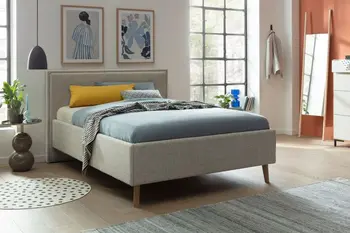 Ein hell graues Polsterbett in einem Schlafzimmer