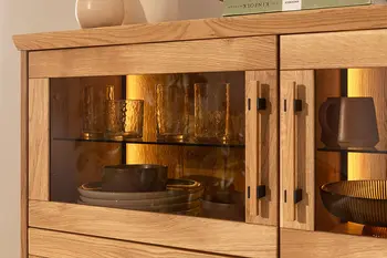Highboard aus massiver Wildeiche mit abgedunkelten Glaseinsätzen und stimmungsvoller, integrierter Beleuchtung.