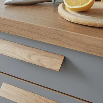 Nahaufnahme eines Küchenschranks mit Holzarbeitsplatte und Griffen aus Holz, mit Fronten in Grau.&nbsp;