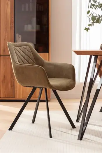Armlehnstuhl mit Lederbezug in dunklem beige, Rautensteppung an der Rückenlehne und schwarzem Metallgestell an einem Esstisch.