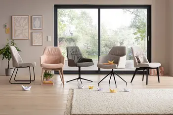 Fünf Stühle mit und ohne Armlehne in rosa und grauem Stoff bezogen mit Füßen aus Holz oder in schwarz in einer Reihe.