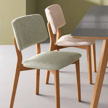 Zwei Esszimmerstühle im Skandi Look nebeneinander mit naturfarbenem und grünem Bezug.