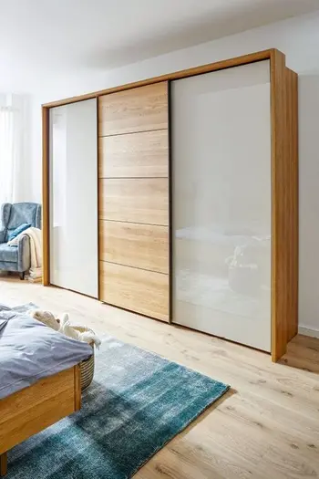 Dreitüriger Kleiderschrank aus Massivholz mit Glastüren.