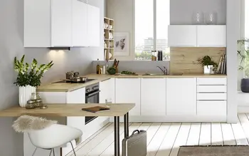 Große moderne Küche in L-Form mit weißen Fronten und hellem Holz als Arbeitsplatte.&nbsp;