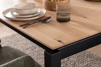 Ecke eines Massivholztisches aus Eiche, der ein schwarzes Metallgestell hat.