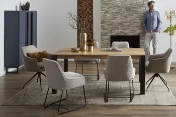 Moderner Massivholz Esstisch, um den herum graue Schalenstühle stehen in einem hellen Raum in dem ein Mann an einer Wand lehnt.