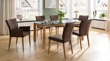 Helles Esszimmer mit schönem Holztisch mit Glasplatte und 6 braunen Stühlen. 