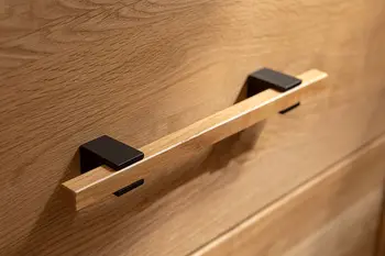 Detailaufnahme von einem Griff eines Sideboards aus schwarzem Metall und Holz.