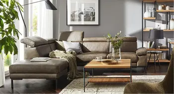 Stylisches dunkelbraunes Ledersofa mit Liegeflaeche in gemuetlich eingerichtetem Wohnzimmer.