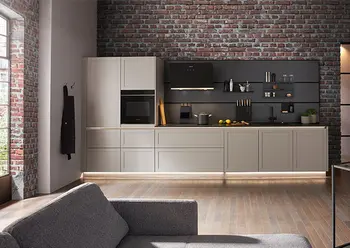 Moderne helle Küche mit dunkler Nischenrückwand vor einer Backsteinwand.