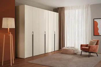 Gemütliches Schlafzimmer mit großem Kleiderschrank mit beigen Fronten neben Ankleidesessel.