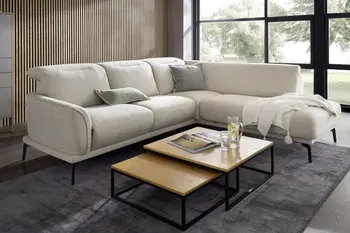 Cremefarbenes Ecksofa mit klappbaren Kopfstützen in einem hellen Raum mit zwei übereinander stehenden Couchtischen.