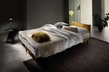 Schlafsofa, das zum Bett umgebaut ist mit einem Bezug in der Farbe Cognac und dekoriert mit weißer und beiger Decke und Kissen in weiß, beige, cognac und schwarz-weiß.