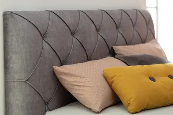 Dunkelgraues Kopfteil eines Polsterbettes mit Steppung