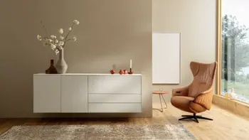 Moderner Relaxsessel in Cognac farbenem Leder neben einem weißen Sideboard.