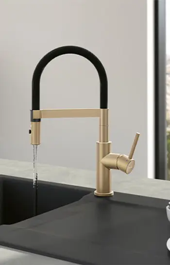 Schwarze Keramikspüle mit Goldenem Wasserhahn.