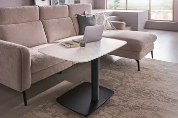 Höhenverstellbarer Couchtisch mit Keramikplatte in Marmoroptik und schwarzem Fuß vor beigem Ecksofa.