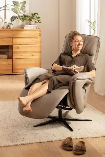 Frau liegt in einem Relaxsessel in grauem Leder, der in Relaxposition ist.