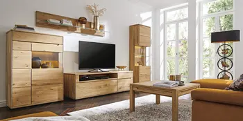 Hoelzerne Wohnwand vor orangefarbener Couch im Wohnzimmer.