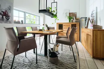 Esstisch mit Massivholzplatte und schwarzem Fußgestell in einem natürlichen Esszimmer mit Sideboard und Highboard aus Massivholz.