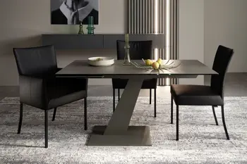 Kleiner Design Esstisch mit schwarzer Tischplatte und grauem schrägem Tischgestell, um den Tisch stehen drei schwarze Stühle.