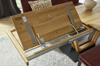 Massivholz Esstisch, bei dem die unter der Tischplatte liegende Verlängerung ausgezogen wird.