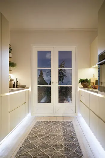 Weiße Küche mit Beleuchtung unterhalb der Leisten.