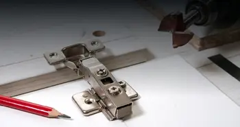 Bohrmaschine und Handwerkerbleistift auf Schranktüre mit Scharnier.