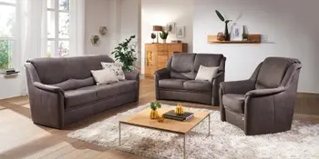 Dunkelbraunes Ecksofa mit passendem Sessel in gemuetlichem Wohnzimmer.