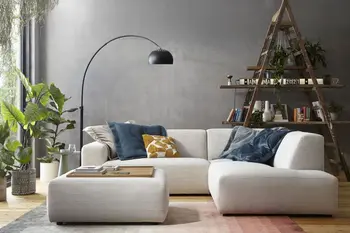 Modernes beiges Ecksofa mit Cordstoff bezogen und einem passenden Hocker, auf dem Sofa sind mehrere Kissen in blau und gelb.