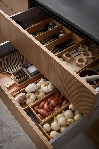 Geöffnete Schubladen der Contur Küche 51.230 mit Einsätzen für Zwiebeln und Besteck.