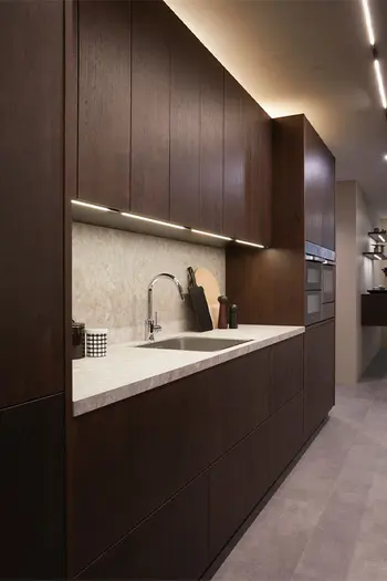 Detail der Spüle in dunkler Küche mit heller Marmor-Arbeitsplatte.