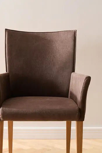 Klassischer Armlehnstuhl in dunkelbraunem Leder mit Holzfüßen.