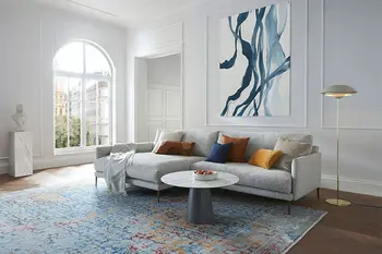 Großes Graues Design Ecksofa in einer Altbauwohnung mit Couchtisch mit runder Tischplatte im Marmor Optik.