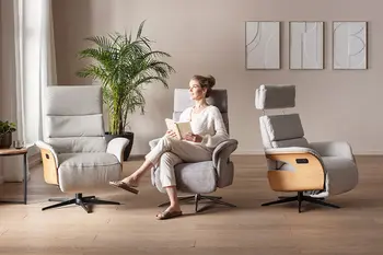 Eine Frau sitzt auf dem mittleren von drei nebeneinander stehenden hellgrauen Relaxssessel mit Holzverkleidung an den Armlehnen außen.