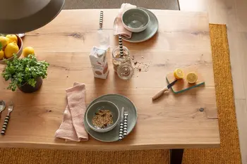 Esstisch aus massiver Eiche mit Baumkante, auf dem Geschirr steht und eine Blumenvase.