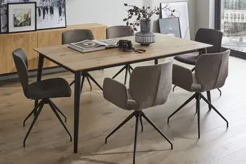 Sechs moderne Schalenstühle mit und ohne Armlehne in Grautönen und schwarzem Fußgestell um einen Holz Esstisch in einem hellen Raum.