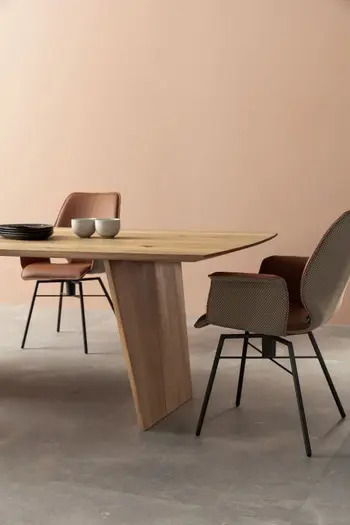 Massivholz Esstisch mit Tischplatte in organischer Form, an dem zwei moderne Schalenstühle stehen.