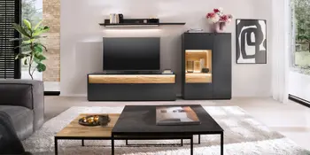 Beleuchtete schwarze Wohnwand mit Holzakzenten und dazugehoerigem Couchtisch in hellem Wohnzimmer.
