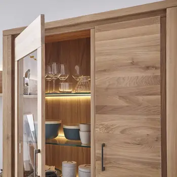 Geöffnete Glastür einer Vitrine aus Massivholz mit einer Glastür und Holztür und beleuchteten Glasregalböden.