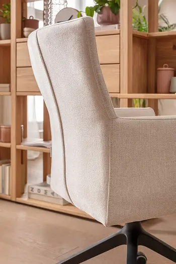 Ansicht der ergonomischen Rückenlehne eines Armlehnstuhls mit beigem Stoff.