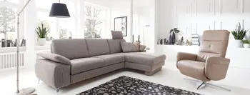 Graues Ecksofa mit Kopfstütze und silbernen Füßen neben einem beigen Drehsessel.